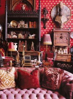 a living room filled with lots of furniture and red wallpapered walls covered in pictures