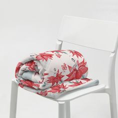 a white chair with a red flowered blanket on it