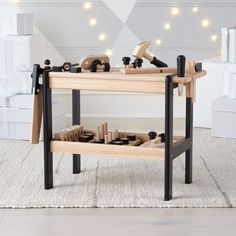 a wooden workbench with tools on it in front of a white wall and string lights