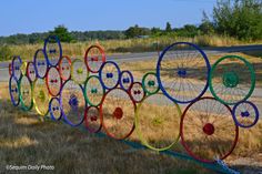 a row of colorful spokes sitting on the side of a road next to a grass covered field