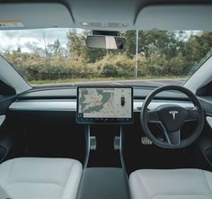 the interior of a car with an electronic device in the center and steering wheel visible