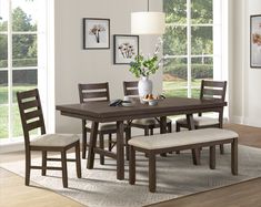 a dining room table with chairs and a bench in front of the window on a rug