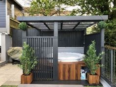 an outdoor hot tub in the middle of a yard with potted plants on either side