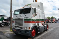 a semi truck is parked on the side of the road with other trucks behind it