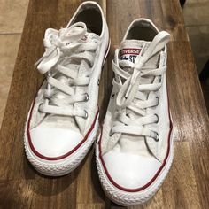 a pair of white sneakers sitting on top of a wooden floor