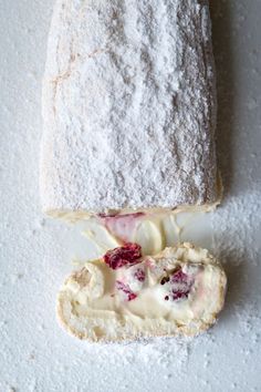 a piece of bread with cream and strawberries on it sitting next to a baguette