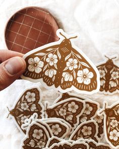 a hand holding a brown and white butterfly sticker next to some other stickers