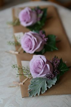 three purple flowers are placed on top of a piece of brown paper and tied with twine