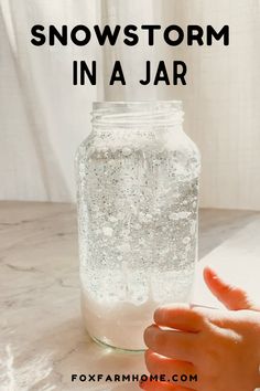 someone is holding their hand up to a jar filled with snowstorm in a jar