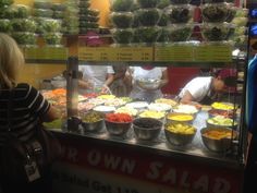 people are standing in front of a salad stand