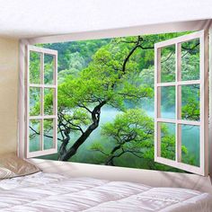 an open window with a view of a tree and lake outside it, in front of a white bed