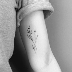 a black and white photo of a woman's arm with a flower tattoo on it