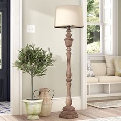 a floor lamp next to a potted plant on a table in front of a door