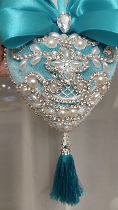 a heart shaped ornament decorated with pearls and tassels