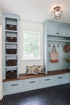 a room filled with lots of white cabinets and drawers next to a window on top of a tiled floor