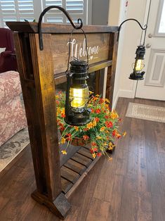 a lantern is sitting on top of a wooden crate with flowers in it and the words welcome