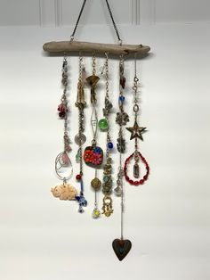 a wooden branch hanging from the ceiling with various necklaces and charms attached to it