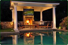 an outdoor fireplace is lit next to a pool