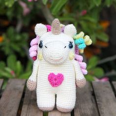 a crocheted stuffed animal with a heart on it's chest sitting on a wooden table