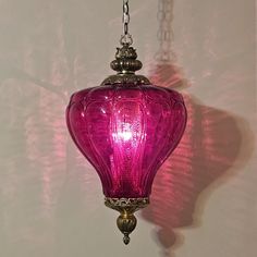 a pink glass light hanging from a chain