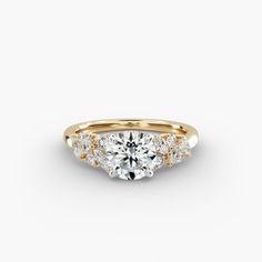 a three stone engagement ring with diamonds on the band and side stones in yellow gold