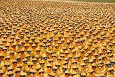 a large group of people wearing sun glasses and yellow shirts are standing in the middle of a field