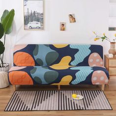 a living room with a colorful couch and rugs on the floor, in front of a white wall