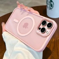 a pink iphone case sitting on top of a wooden table next to a coffee cup