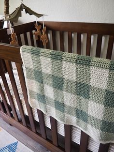 a crocheted baby blanket hanging from the side of a crib