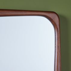 a wooden frame mirror mounted on a green wall