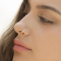 a close up of a woman with a nose piercing on her nose and one eye closed