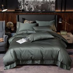 a bed with black sheets and pillows in a room next to a gray chair, green wall