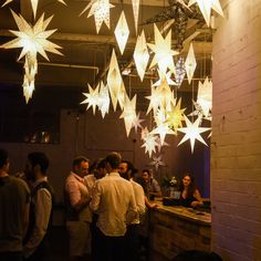 a group of people standing around a bar under paper stars hanging from the ceiling above them