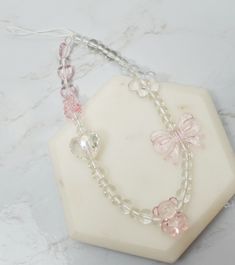 two bracelets with pink and white beads on a hexagonal base, sitting on a marble slab