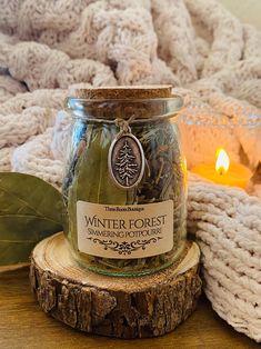 a glass jar filled with green tea sitting on top of a wooden table next to a candle