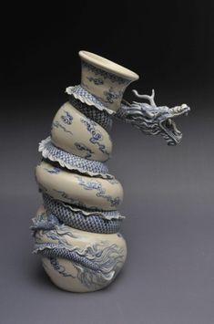 a white and blue vase sitting on top of a pile of stacked containers with dragon heads