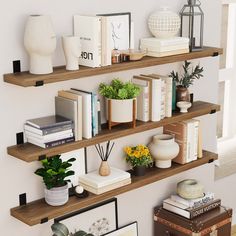 three wooden shelves filled with books and plants