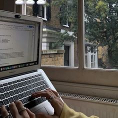 a person typing on a laptop in front of a window