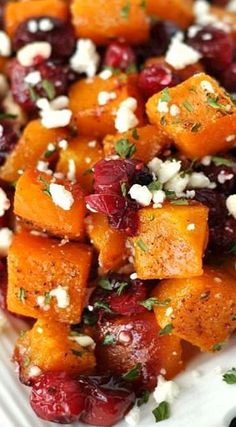 a white plate topped with sweet potatoes, cranberries and feta cheese on top