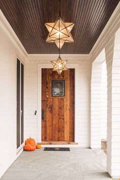 a wooden door with two pumpkins on the front step and a lantern hanging from the ceiling