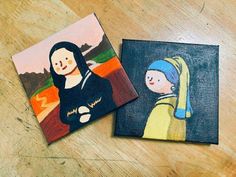 two small paintings on wooden table with one painted like a woman and the other as a child