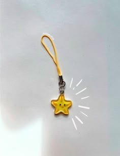 a yellow star shaped keychain hanging from a clip on a white table top