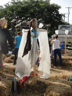 some people are standing around in the hay with hats and scarves on their heads