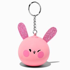 a pink keychain with ears and eyes on it's face, sitting in front of a white background