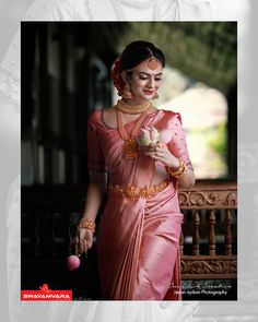 a woman in a pink sari holding a flower