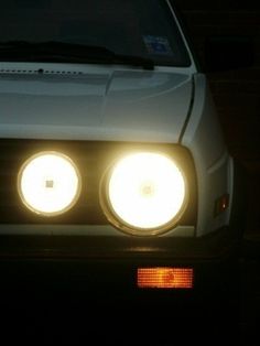 the headlights of a white car are glowing