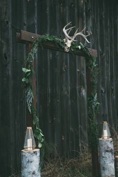 a deer head is mounted on the back of a wooden frame with candles and greenery