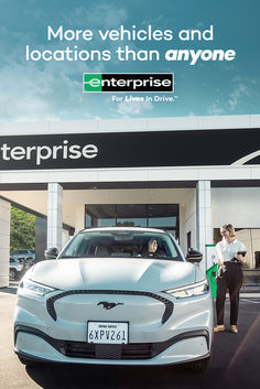 two people standing next to a white car in front of a enterprise sign that reads more vehicles and locations than anyone