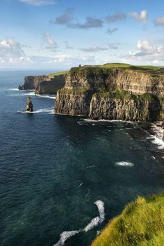 the ocean is blue and green with waves coming in from the rocks on the shore