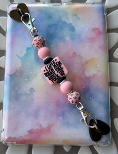 a pink and black beaded keychain with some charms attached to it